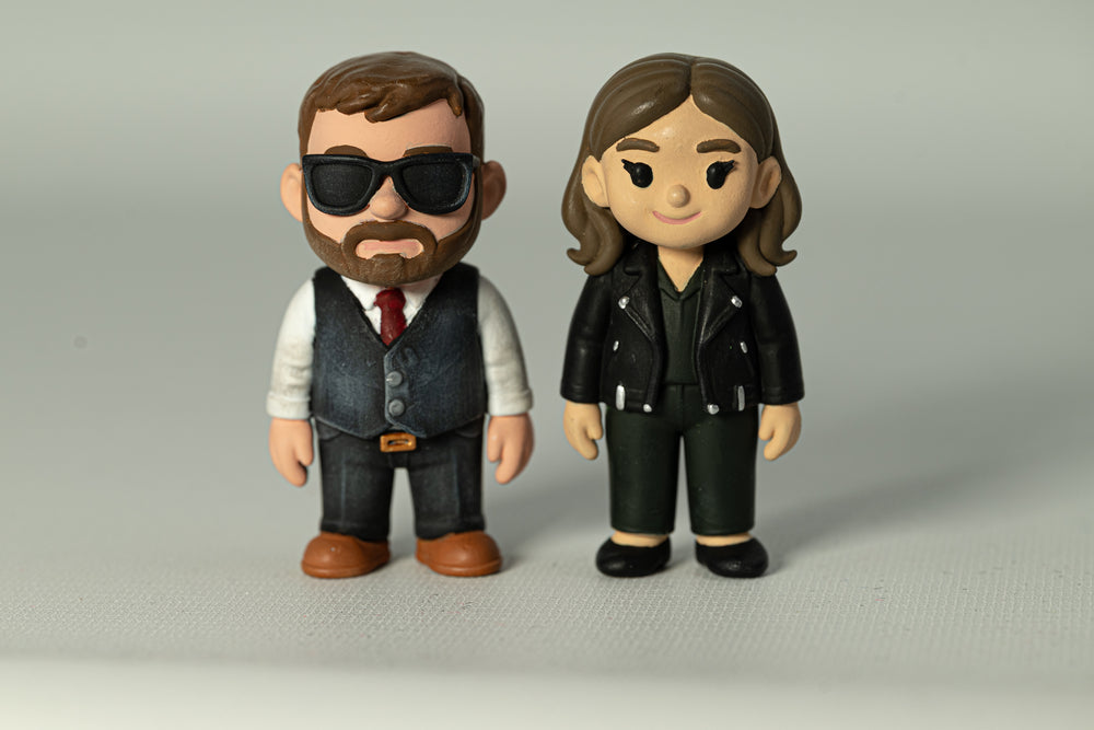 Two painted character figures: one wearing sunglasses and a waistcoat, the other a black jacket.